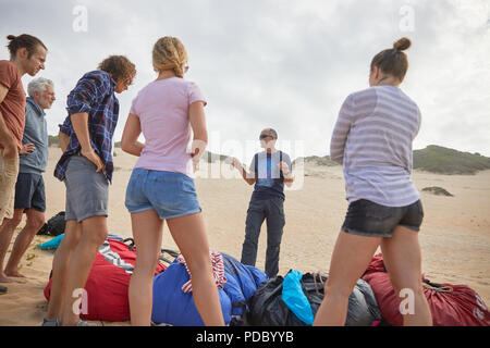 Male paragliding instructor talking to students on beach Stock Photo