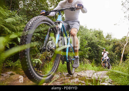 Man mountain biking on muddy trail Stock Photo