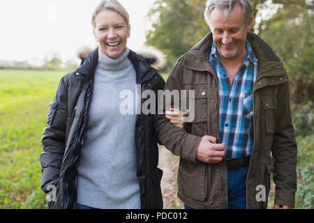 Happy mature couple walking arm in arm in park Stock Photo