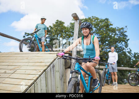 Smiling young woman mountain biking at obstacle course Stock Photo