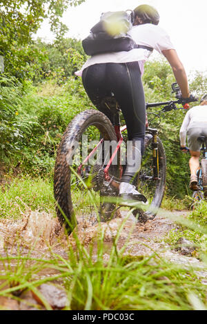 Woman mountain biking on muddy trail Stock Photo