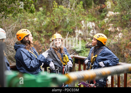 Smiling women friends talking, waiting to zip line Stock Photo