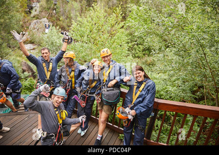 Portrait enthusiastic friends zip lining in woods Stock Photo