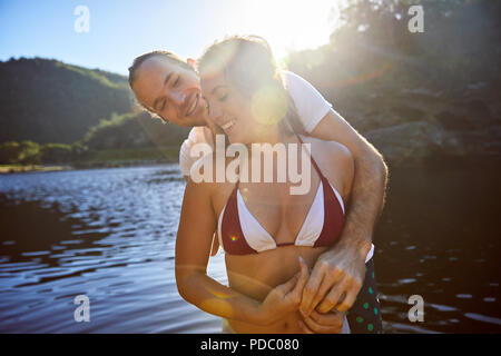 Affectionate couple hugging at sunny summer lake Stock Photo