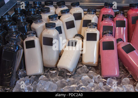 close up view of various types of bottles with smoothies in refrigerator with ice cubes Stock Photo