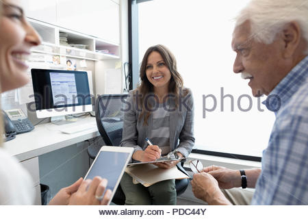 Female doctor talking to senior patient with daughter in clinic office