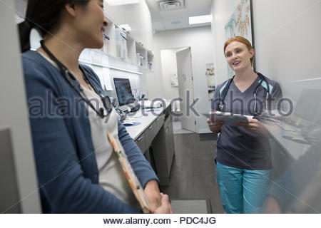 Female doctor and nurse discussing medical record in clinic