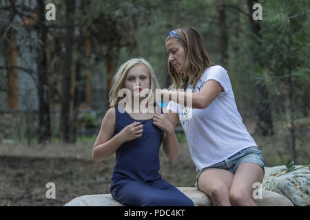 Young female wearing aunt's  dress, as aunt arranges the dress for a photo shot, outside on the rocks. Both attractive, vertical and both model releas Stock Photo