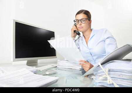 business woman working at office desk with computer reads a documents and speak on the phone, isolated on white background Stock Photo