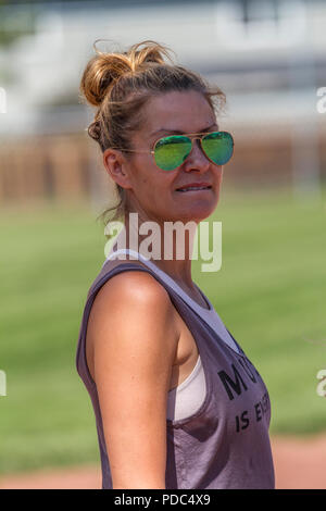 Attractive woman, in sunglasses and wearing tank top, hair up in bun, looking at camera, profile shot, close up. Model released. Stock Photo