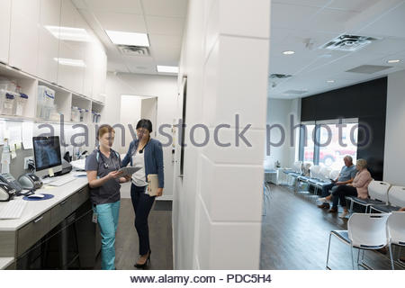 Female doctor and nurse discussing medical record in clinic