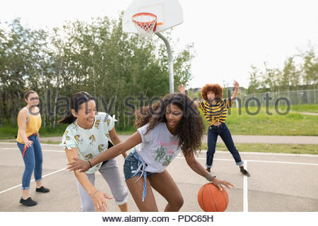 Teenage girl friends playing basketball at park basketball court