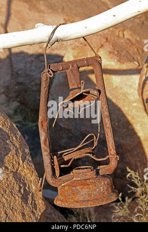 Rusty old oil lamp hanging from a dead branch. Stock Photo