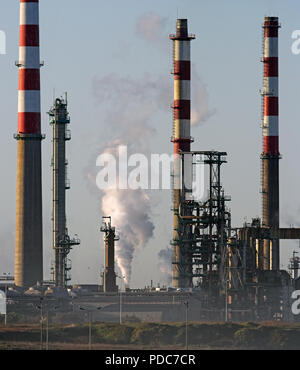 Industrial pipes and chimneys from a big oil refinery seeing steam and heat Stock Photo