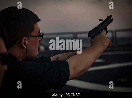 180803-N-UY653-545  MEDITERRANEAN SEA (Aug. 3, 2018) Fire Controlman 3rd Class Dylan Barnard fires a 9mm handgun during a live-fire qualification course aboard the Arleigh Burke-class guided-missile destroyer USS Carney (DDG 64) Aug. 3, 2018. Carney, forward-deployed to Rota, Spain, is on its fifth patrol in the U.S. 6th Fleet area of operations in support of regional allies and partners as well as U.S. national security interests in Europe and Africa. (U.S. Navy photo by Mass Communication Specialist 1st Class Ryan U. Kledzik/Released) Stock Photo