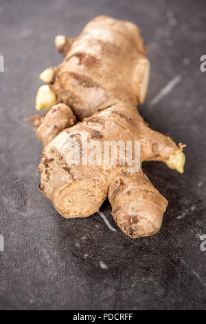Whole ginger roots on dark old stone background table, space for text. Stock Photo