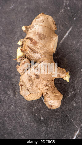 Whole ginger roots on dark old stone background table, space for text. Stock Photo