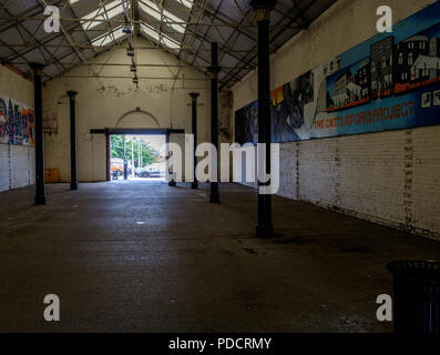 Large empty warehouse with some graffiti on one wall Stock Photo