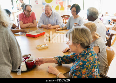 Senior friends playing games and drinking tea at table in community center Stock Photo