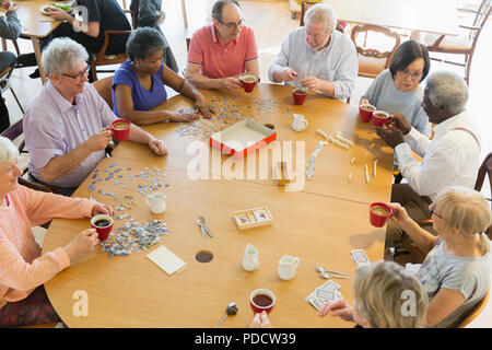 Senior friends playing games at table in community center Stock Photo