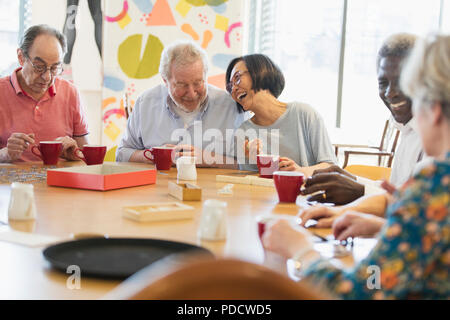 Happy senior friends playing games at table in community center Stock Photo