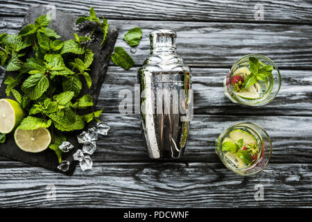 top view of shaker, glasses and ingredients for strawberry kiwi mojito on wooden table Stock Photo