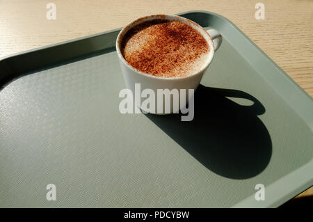 cappuccino coffee in white mug on grey plastic tray Stock Photo