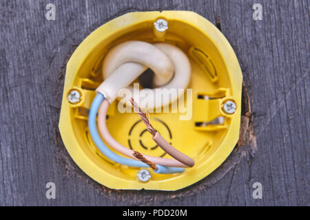 Two wires in yellow socket box of wall 