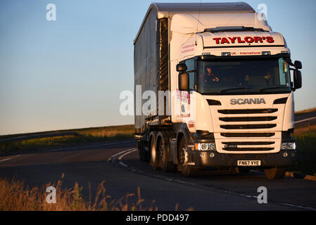 Scania truck pulling a curtainsider trailer takes a corner on the Woodhead Pass, Yorkshire, at dusk Stock Photo
