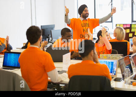 Hackers cheering, coding for charity at hackathon Stock Photo