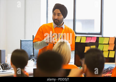 Hacker in turban leading meeting, coding for charity at hackathon Stock Photo