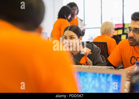 Hackers at laptops coding for charity at hackathon Stock Photo