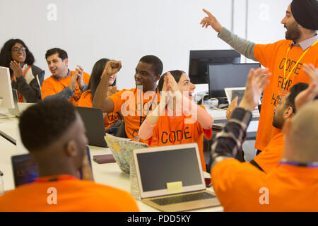 Happy hackers cheering and celebrating, coding for charity at hackathon Stock Photo