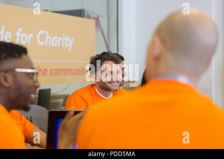 Smiling hacker coding for charity at hackathon Stock Photo