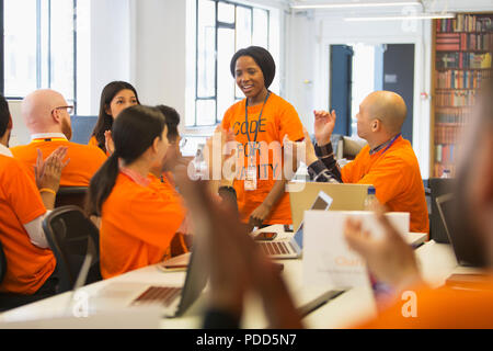 Hackers cheering for woman, coding for charity at hackathon Stock Photo