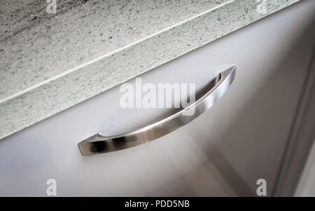 Stainless steel drawer handle in a modern domestic kitchen. Stock Photo