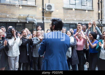 Business people cheering for businessman in courtyard Stock Photo