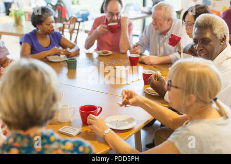 Friends drinking tea and playing games at table in community center Stock Photo
