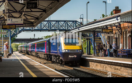 Passengers waiting on the platform as a class 43 train in First Great Western livery pulls into a railway station. Stock Photo