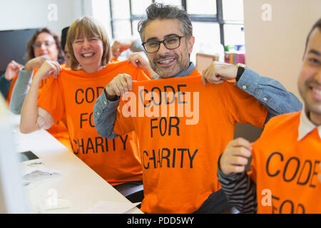 Portrait confident hackers in t-shirts coding for charity at hackathon Stock Photo