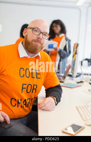 Portrait confident hacker coding for charity at hackathon Stock Photo