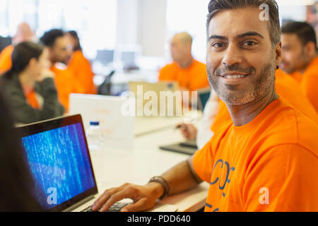 Portrait confident hacker at laptop coding for charity at hackathon Stock Photo