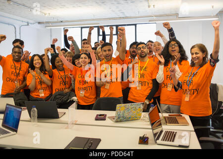 Portrait confident hackers cheering, coding for charity at hackathon Stock Photo