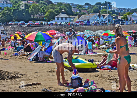 Crowded & busy summertime beach scene with a collection of colourful sun unbrellas at Saundersfoot, Pembrokeshire Stock Photo