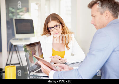 Middle aged businessman using digital tablet while working together financial assistant businesswoman. Stock Photo
