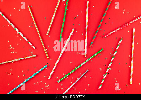 New Year or Christmas pattern flat lay top view Xmas holiday 2019 celebration drinking cocktail party straws red paper golden sparkles background. Tem Stock Photo