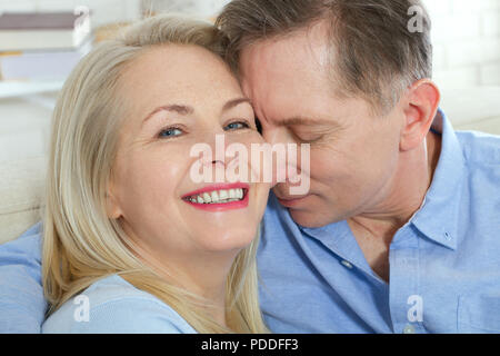 Middle aged couple relaxing on couch smiling at camera at home in the living room Stock Photo