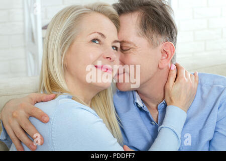 Closeup photo of cheerful excited happy happily happy with toothy shining smile blond attractive woman and man, he hugs her from behind and kisses Stock Photo