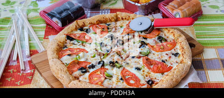 The composition on the cutting Board pizza and sushi for fast food. Wooden sticks for sushi. Fresh, hot and nutritious food. Stock Photo