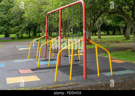 A set of four chidren's swings in a country park with mature Scottish trees Stock Photo